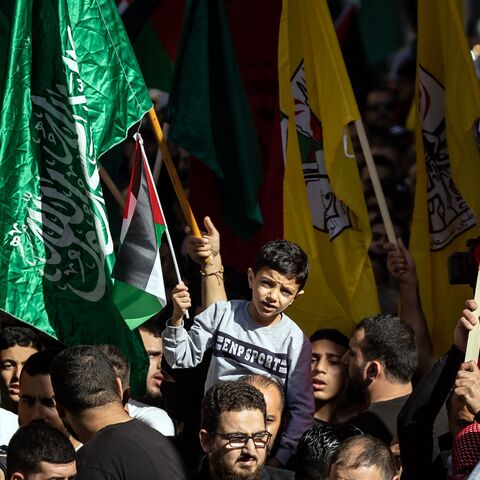 Palestinians lift flags of the Hamas and Fatah groups as they demonstrate in Ramallah in the occupied West Bank on November 10, 2023, amid ongoing battles between Israel and the Hamas movement in the Gaza Strip. 